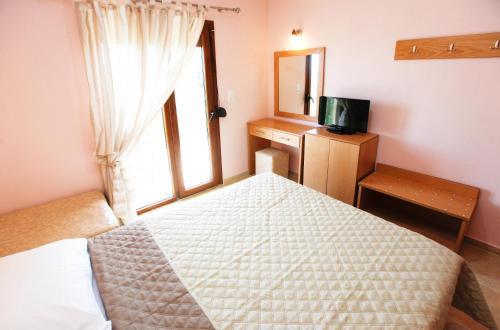 a bedroom with a bed and a window and a television at Asteras Kalives in Skala Potamias
