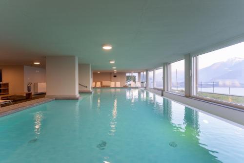 a large swimming pool with blue water in a building at Valarin Luxury Apartments & Wellness, Vercana by Rent All Como in Vercana