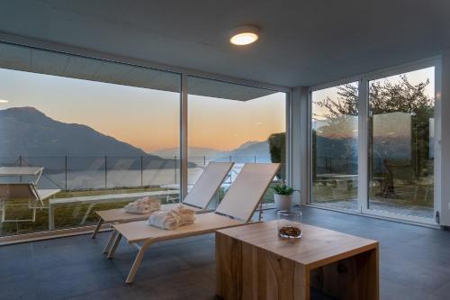 a room with a chair and a table and windows at Valarin Luxury Apartments & Wellness, Vercana by Rent All Como in Vercana