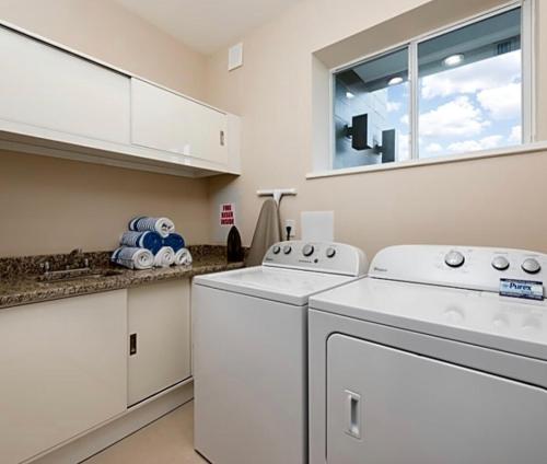 a laundry room with white appliances and a window at Super Close to Disney Magic Stays in Orlando