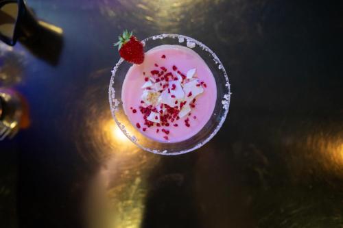 a pink drink with a strawberry on a table at Blakeney House in Blakeney