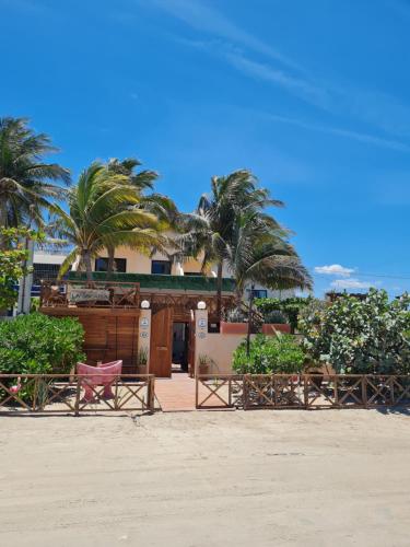a building on the beach with chairs and palm trees at La Bocania in Progreso