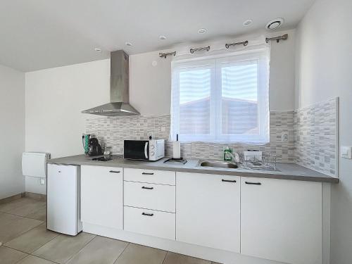 Una cocina blanca con fregadero y ventana. en Joli Studio proche CNPE du Blayais, en Saint-Aubin-de-Blaye