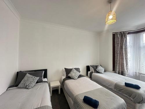 a room with three beds and a window at Spacious Family Friendly 4-Bed Holiday Home in Ilford