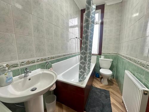 a bathroom with a sink and a tub and a toilet at Spacious Family Friendly 4-Bed Holiday Home in Ilford