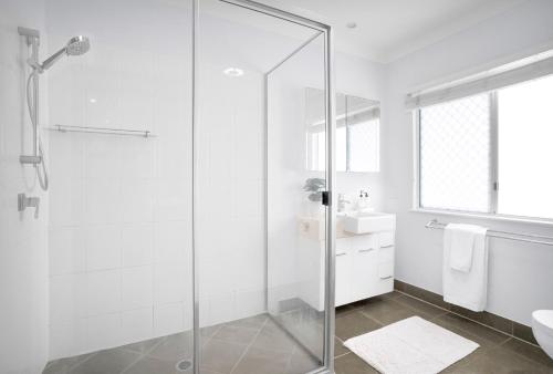 a bathroom with a glass shower and a sink at Palm Cove Studio Apartments in Palm Cove