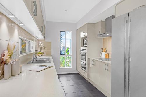 a kitchen with white cabinets and a window at Palm Cove Studio Apartments in Palm Cove