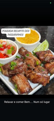ein Teller mit Fleisch und Schüsseln mit Gemüse in der Unterkunft Pousada dos Passarinhos in Água Boa