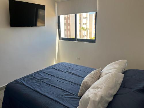 a bedroom with a bed and a tv and a window at Increible departamento NUEVO en Mazatlán in Mazatlán