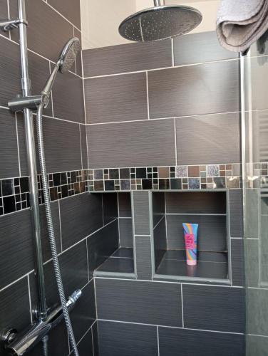 La salle de bains est pourvue d'une douche avec du carrelage noir. dans l'établissement Le CosyNew 3, à Calais