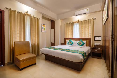 a hotel room with a bed and a chair at Treebo Urban Oasis Inn, Sixmile in Guwahati