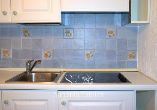 a kitchen with a sink and blue tiles on the wall at Rainbow House - Fronte Spiaggia in Porto Rotondo