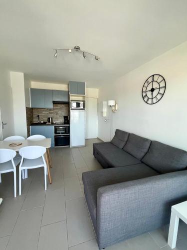 un salon avec un canapé et une cuisine dans l'établissement Appartement vue mer et marina, Loggia - Parking, à Courseulles-sur-Mer