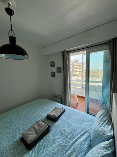 une chambre avec un lit et une grande fenêtre dans l'établissement Appartement vue mer et marina, Loggia - Parking, à Courseulles-sur-Mer