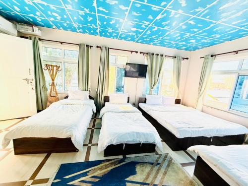 - une chambre avec 3 lits et un plafond bleu dans l'établissement Hotel Mantra and Adventure, à Sauraha