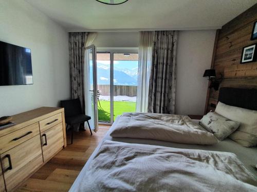 a bedroom with a bed and a sliding glass door at Kitzbüheler Alpenlodge Bergblick Suite in Mittersill