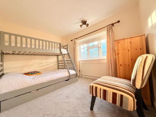 a bedroom with a bunk bed and a chair at New Forest Cozy 3-Bed Family Cottage, PaultonsPark in Bartley