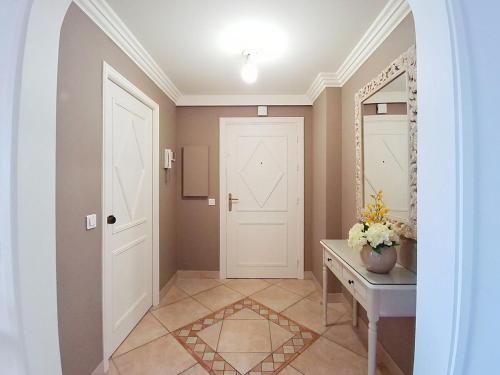 un couloir avec une porte blanche et une table dans l'établissement Superbe appartement 3P rénové dans le Domaine du Grand Duc, à Mandelieu-la-Napoule