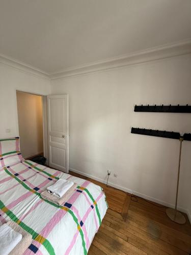 une chambre avec un lit avec une couverture rayée dans l'établissement Appartement parisien 2 pièces, à Paris