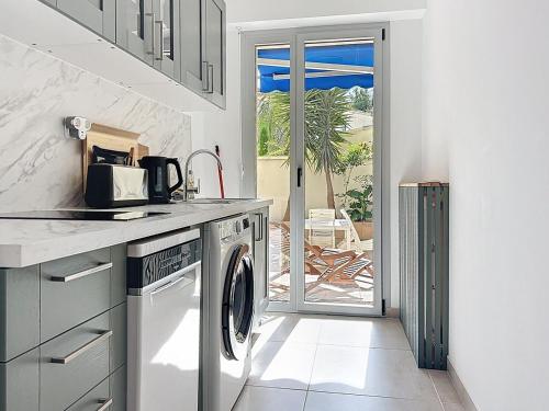une cuisine avec lave-linge et sèche-linge à côté d'une terrasse dans l'établissement Appartement climatisé, 2 chambres, plage Mourillon, à Toulon