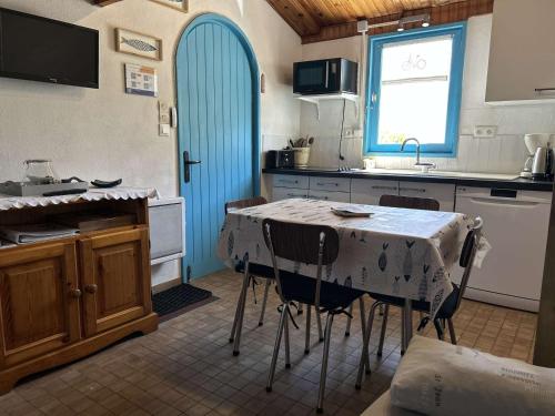 une cuisine avec une table et des chaises ainsi qu'une porte bleue dans l'établissement Studio Mezzanine à 200m du Port et de la Plage, Cour Privative, Parfait pour 3 Personnes - FR-1-224B-564, à Noirmoutier-en-l'lle