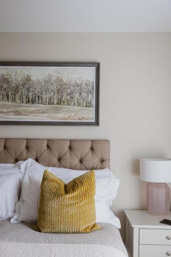 a bed with a yellow pillow and a picture on the wall at White Hart Inn in Brightling
