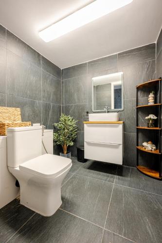 a bathroom with a toilet and a sink and a mirror at Luxury Apartment with Pool in Xagħra