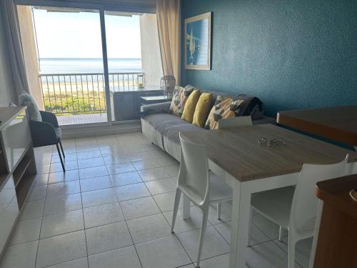 un salon avec une table et un canapé dans l'établissement Appartement 2 pièces avec piscine, garage, et WIFI à La Grande-Motte - FR-1-328-220, à La Grande Motte