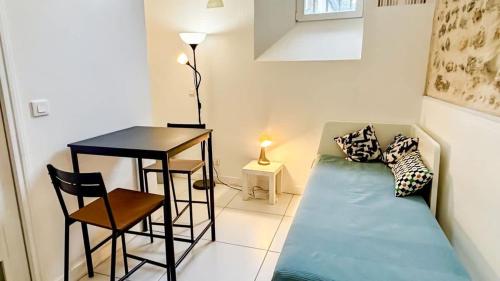 Cette chambre comprend un canapé, une table et un bureau. dans l'établissement Studio au calme hyper centre, à Bordeaux