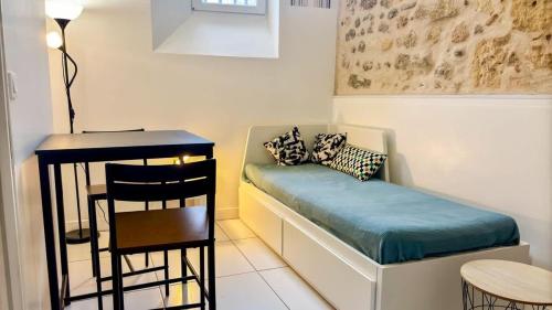 Cette chambre comprend un lit, une table et un tabouret. dans l'établissement Studio au calme hyper centre, à Bordeaux