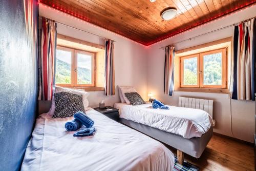 two beds in a room with two windows at Chalet Elisthur in Saint-Jean-dʼAulps