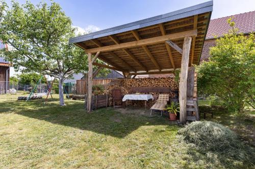 a picnic table under a wooden pavilion in a yard at Unser Ferienhaus Sonnenhof Reudnitz in Friedland