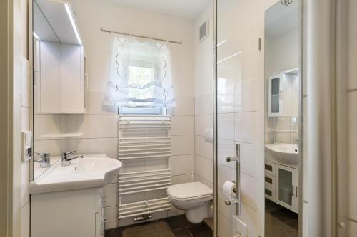 a white bathroom with a toilet and a sink at Unser Ferienhaus Sonnenhof Reudnitz in Friedland