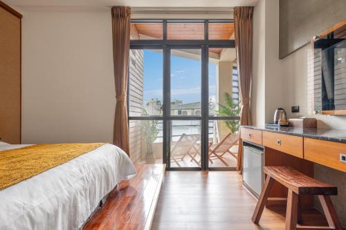 a bedroom with a bed and a kitchen with a balcony at Sun Moon Lake ItaThao Vacation Inn with Elevator in Yuchi