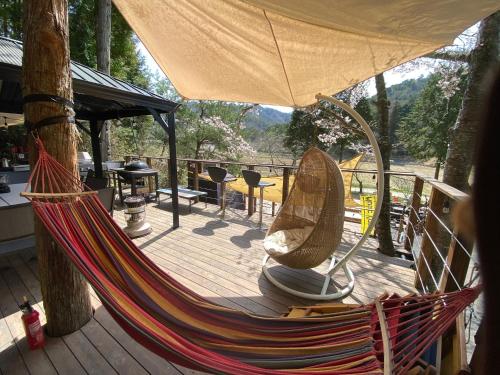 a hammock on a deck with a table and chairs at 貸別荘MUSIC FOREST by MFR in Sasayama