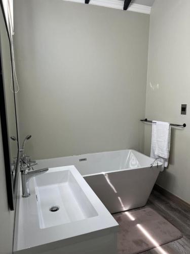 a white bathroom with a tub and a sink at Mountain Pastures Game Lodge in Uniondale