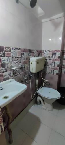 un baño con inodoro y lavabo en Om Sona Guest House, en Digha