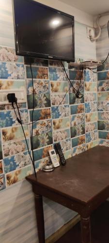 un televisor colgado en una pared con una mesa en Om Sona Guest House, en Digha
