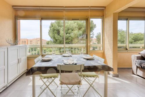 une salle à manger avec une table et des chaises et une grande fenêtre dans l'établissement L'Alisier - climatisé à 5 min de la plage, à Six-Fours-les-Plages