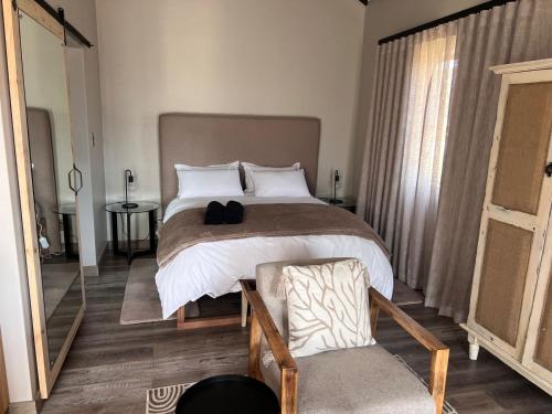 a bedroom with a large bed and a chair at Mountain Pastures Game Lodge in Uniondale