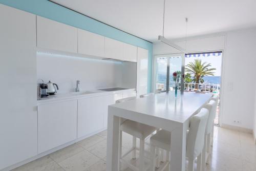 Una cocina blanca con una mesa y sillas blancas. en 3P ST Jean, en Saint-Jean-Cap-Ferrat