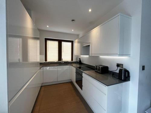 a kitchen with white cabinets and black counter tops at Grosvenor Rd - 2-Bedrooms - Sleeps 5 - Parking in Saint Albans