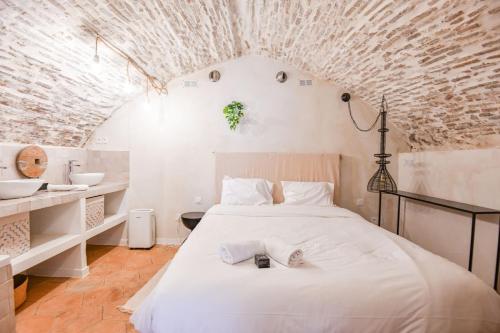 - une chambre avec un grand lit blanc et un mur en briques dans l'établissement Chez Manon - Appart 3 ch avec clim - Saint-Charles, à Marseille