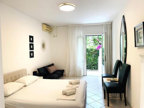 a white bedroom with a bed and a chair at Apartments Stanisic in Herceg-Novi