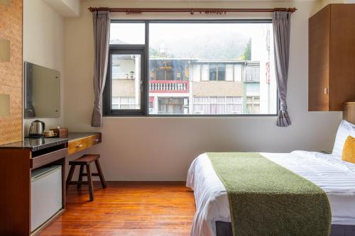 a hotel room with a bed and a window at Sun Moon Lake ItaThao Vacation Inn with Elevator in Yuchi