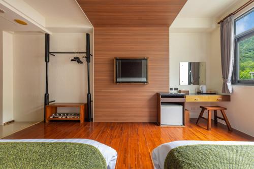 a room with two beds and a tv on a wall at Sun Moon Lake ItaThao Vacation Inn with Elevator in Yuchi