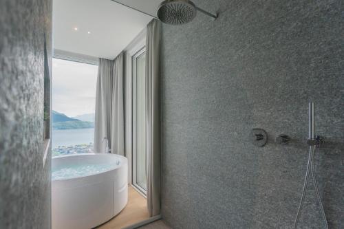 a bathroom with a bath tub and a window at Valarin Luxury Apartments & Wellness, Vercana by Rent All Como in Vercana