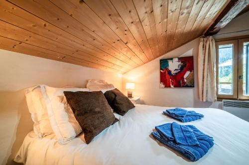 a bedroom with a large white bed with a wooden ceiling at Chalet Elisthur in Saint-Jean-dʼAulps