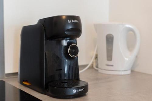 une cafetière assise sur un comptoir à côté d'une tasse dans l'établissement Le Familial - Spacieux - 8p - 10 min Disney, à Bussy-Saint-Georges