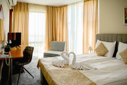 a hotel room with a bed with a desk and a chair at Paradise Hotel & Relax Center in Pomorie